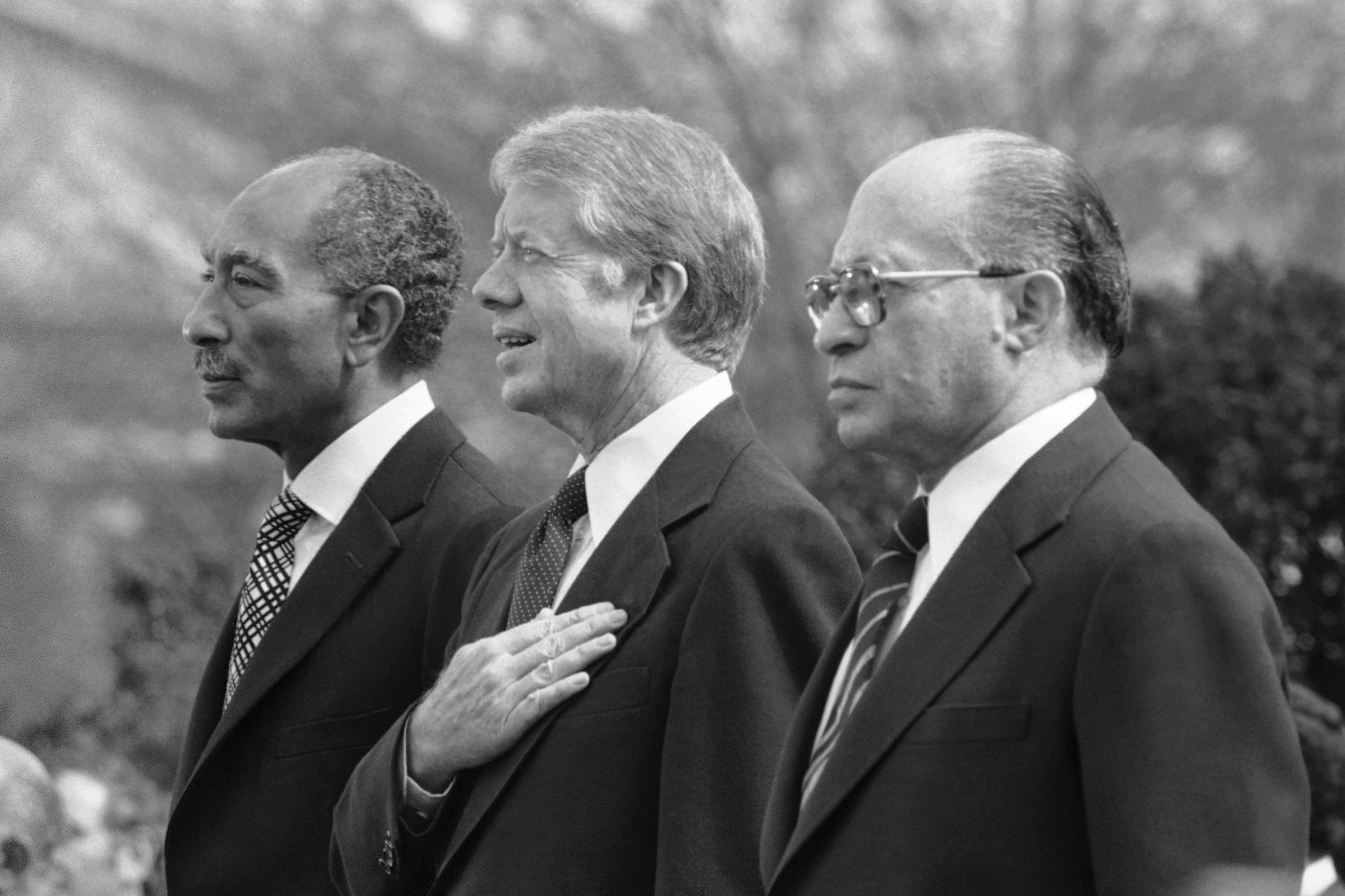 Egyptian President Anwar el-Sadat, left, U.S. President Jimmy Carter, center, and Israeli Prime Minister Menachem Begin stand at attention as the national anthems of their respective countries are played on the north lawn of the White House in Washington, D.C., on Feb. 24, 1979.