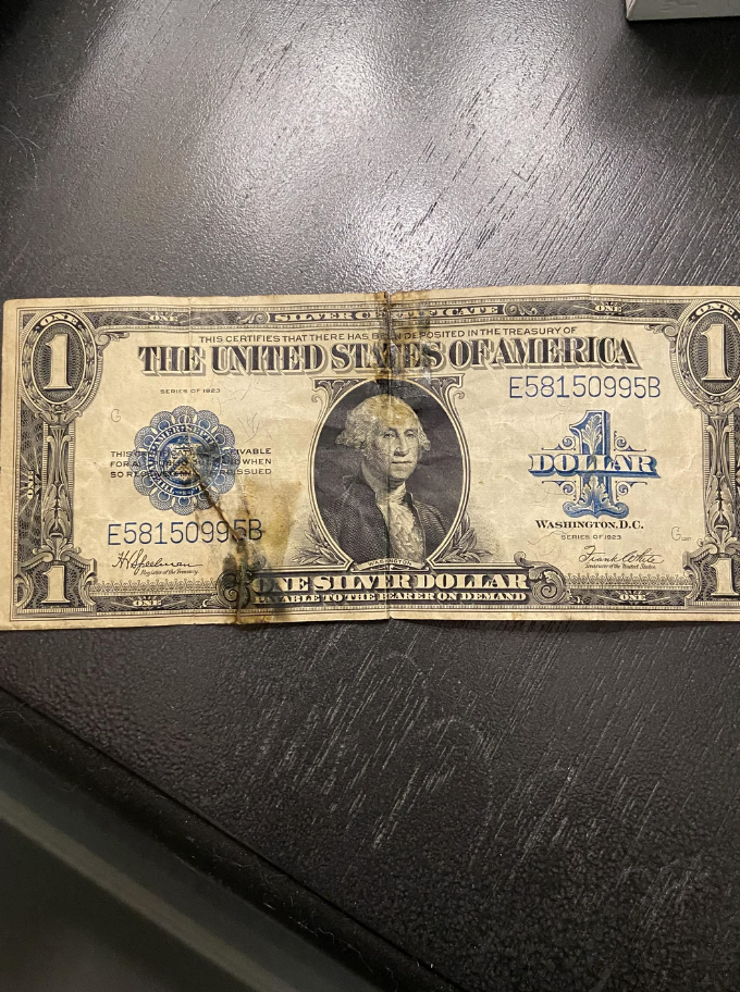 Old U.S. silver certificate dollar with George Washington&#39;s portrait, showing signs of wear and staining