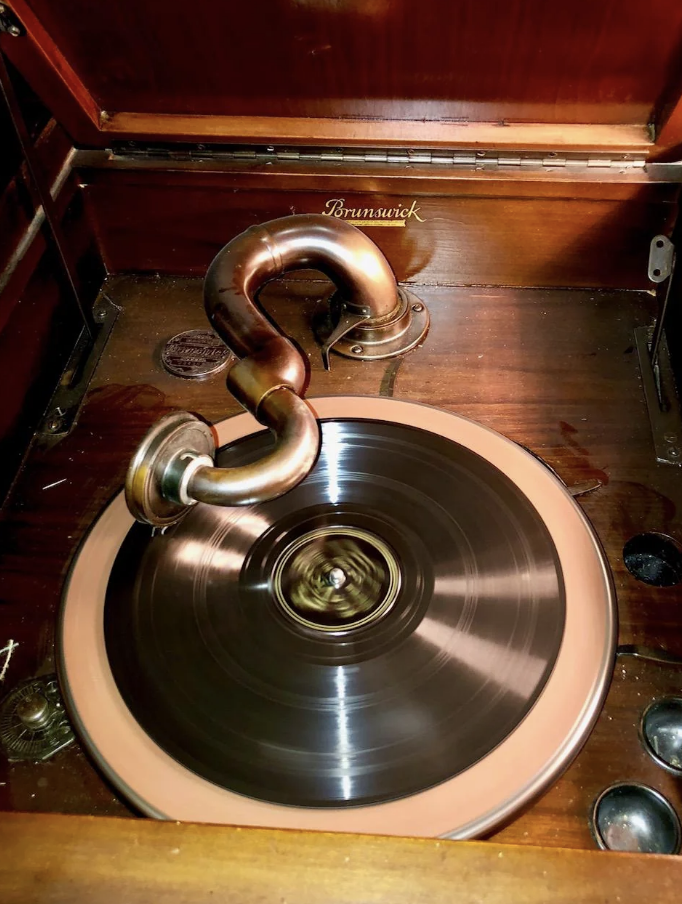 A vintage Brunswick gramophone playing a record, featuring a curved horn and wooden casing, showcasing early 20th-century audio technology