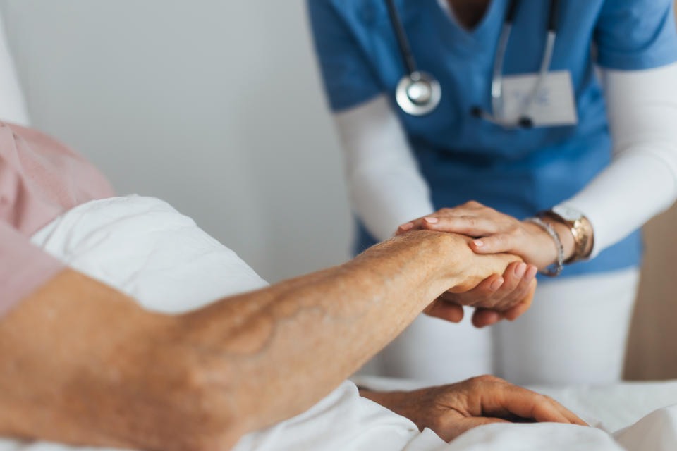 A healthcare professional gently holds a patient's hand, providing comfort and support