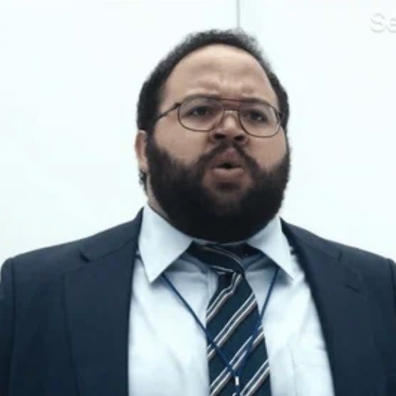 Man with a beard in a suit and tie, looking surprised, standing in a sterile white environment