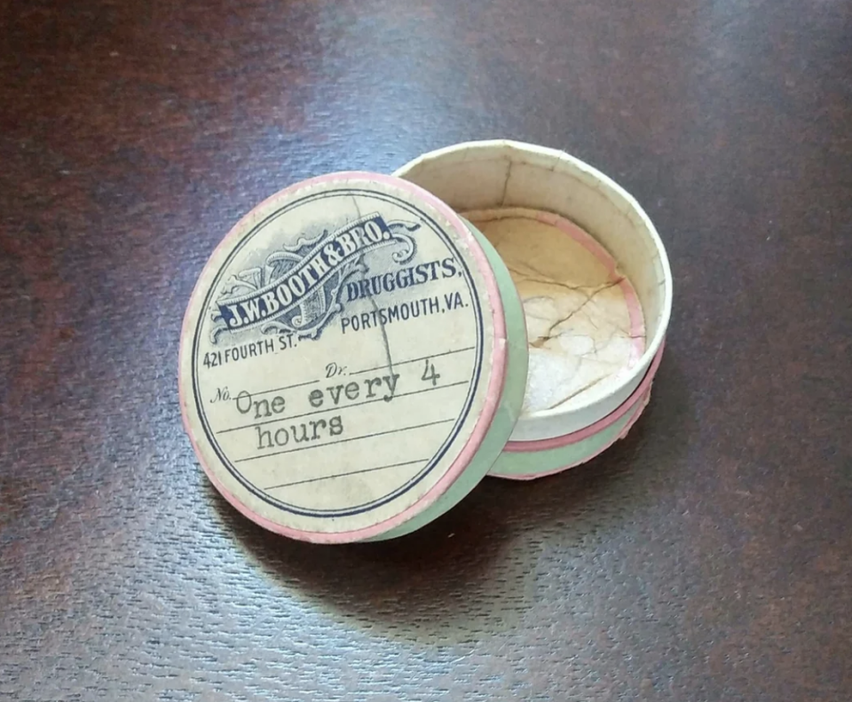 Round vintage pill box labeled &quot;J.W. Booth &amp; Bro. Druggists, Portsmouth, VA,&quot; with &quot;One every 4 hours&quot; instructions, shown open and empty