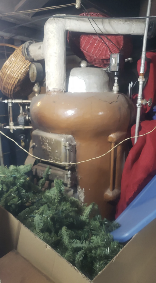 Vintage boiler surrounded by pipes and holiday decorations in a storage area