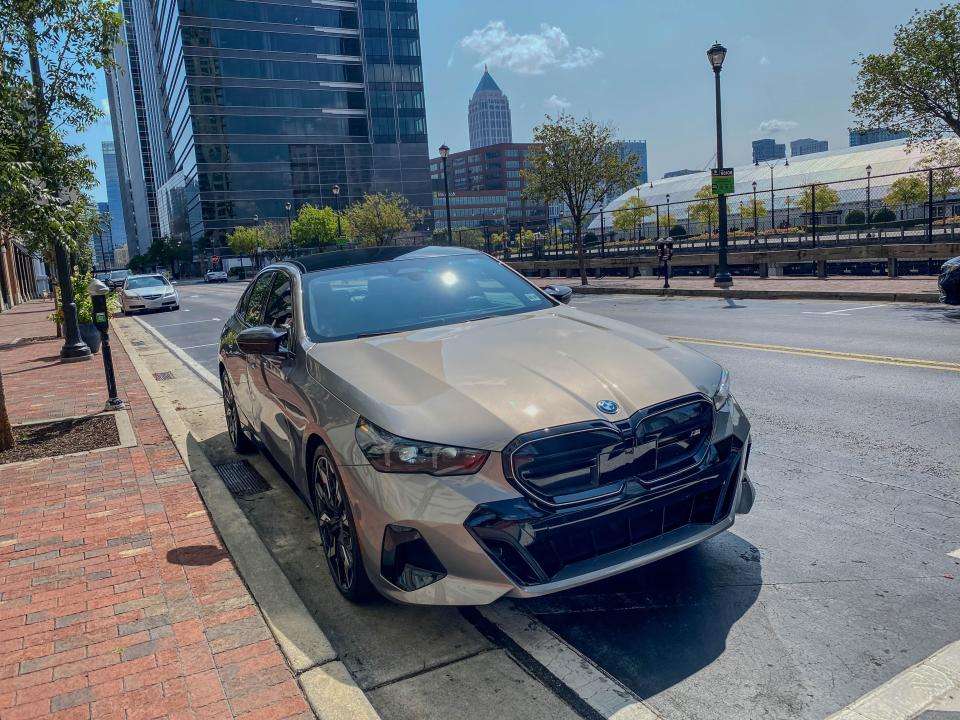 The right front corner of a gray 2024 BMW I5 M60 xDrive EV sports sedan parked on a street.