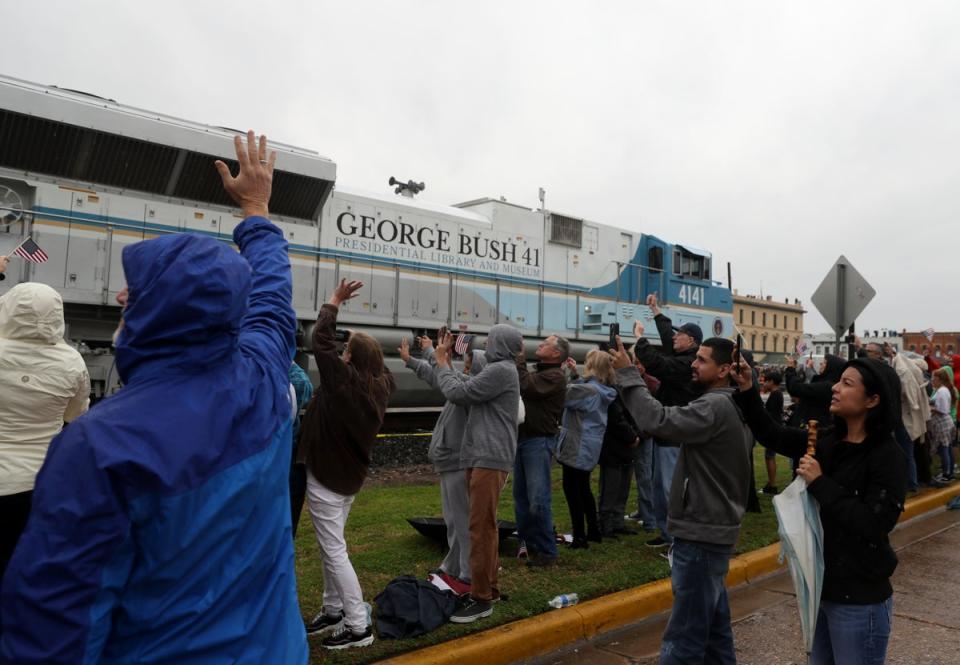 People wave at a train that is carrying the casket of former U.S. President George H.W. Bush to the George H.W. Bush Presidential Library at Texas A&M University on 6 December, 2018 in Navasota, Texas (Getty Images)
