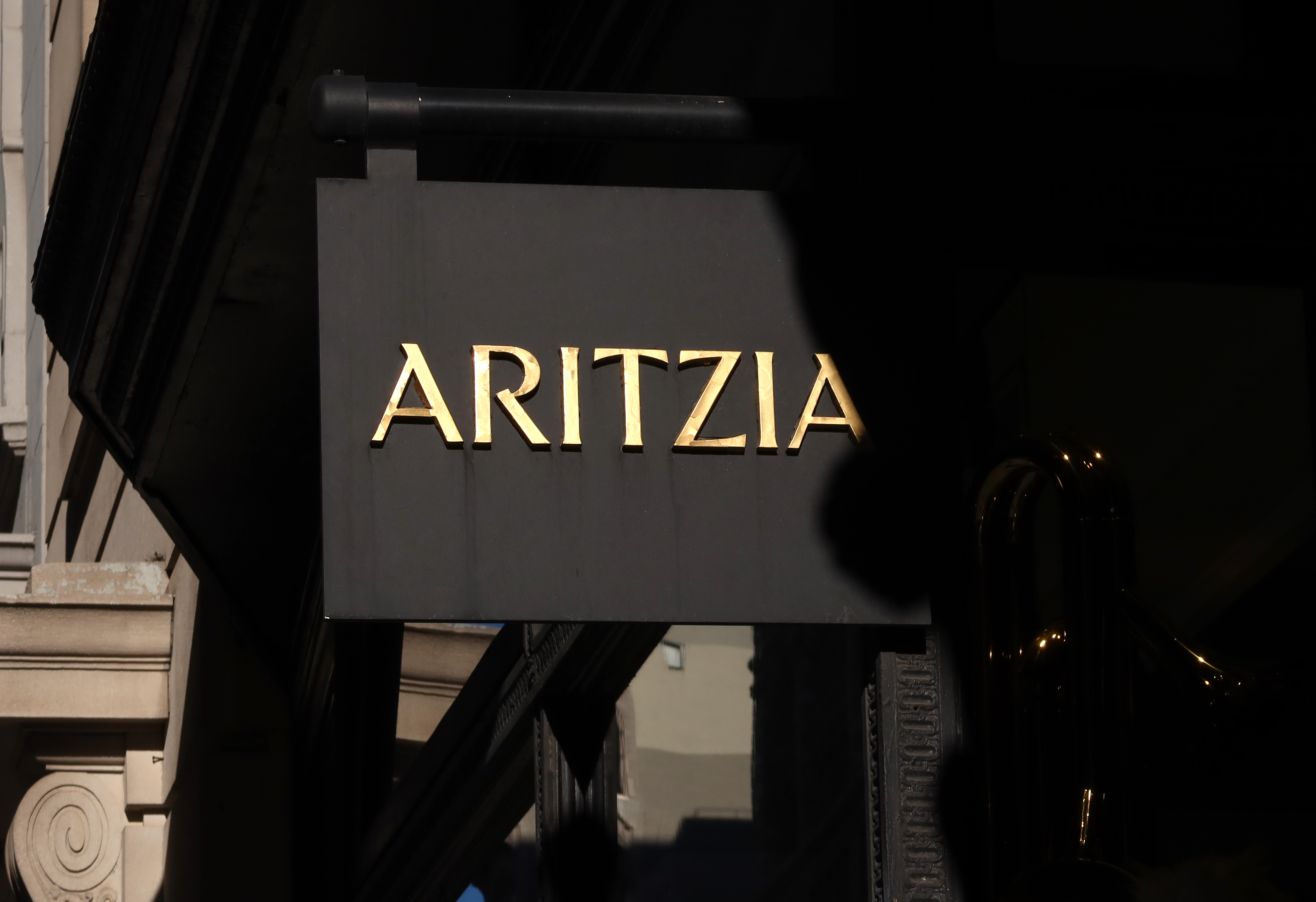 A corporate logo for Aritzia hangs outside their store on 5th Avenue.