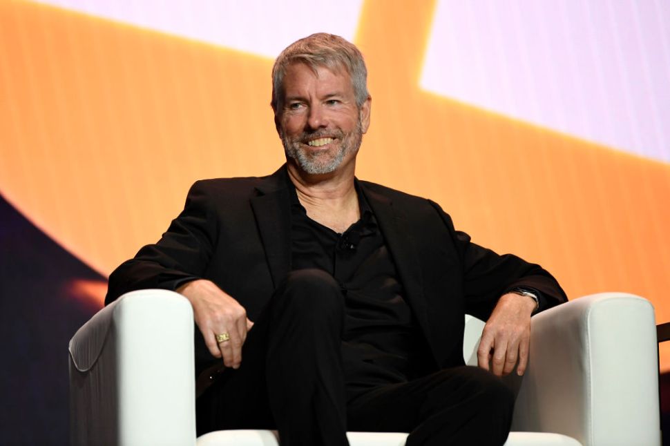 A man in a black outfit sitting in a chair.