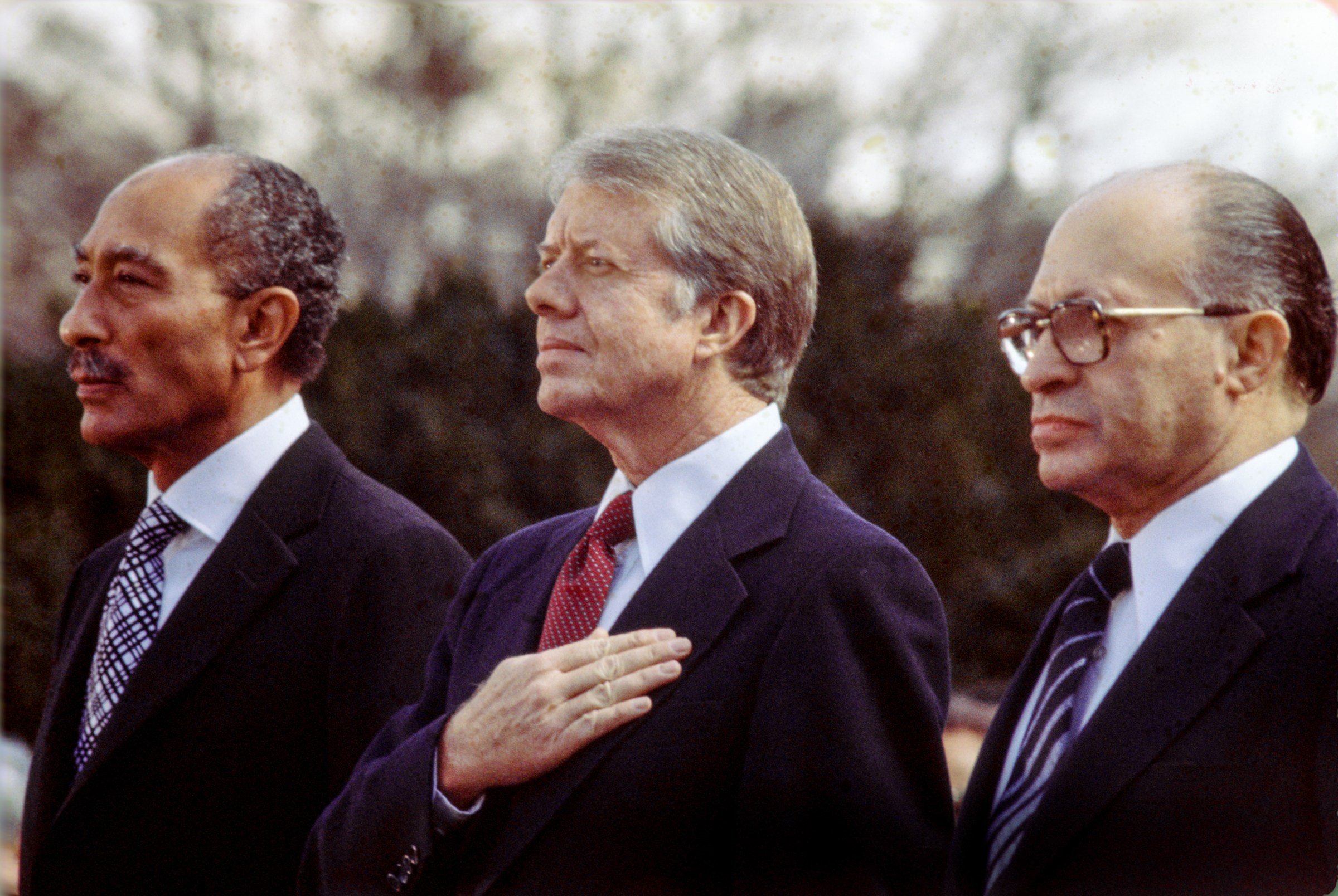 Former Egyptian President Anwar al-Sadat, Jimmy Carter, and former Israeli Premier Menachem Begin listen to the national anthem before signing the Egypt-Israel Peace Treaty on the north lawn of the White House on March 26, 1979.