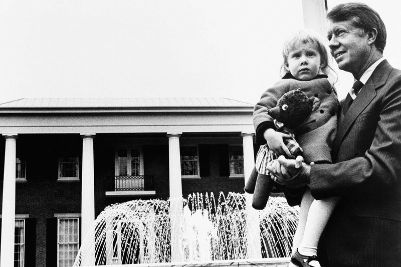 Carter as governor-elect walks the grounds of the governor's mansion in Atlanta in January 1971. In his arms is his daughter, Amy Carter, then 3.