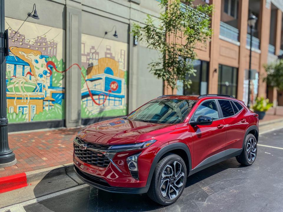 The left front corner of a red 2025 Chevrolet Trax 2RS subcompact SUV parked on the street.