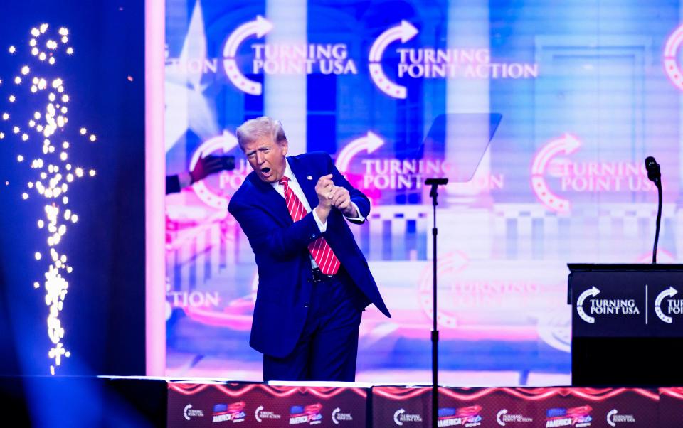 President-elect Donald Trump mimics a golf swing onstage while speaking at the annual AmericaFest in Phoenix on Dec. 22, 2024.