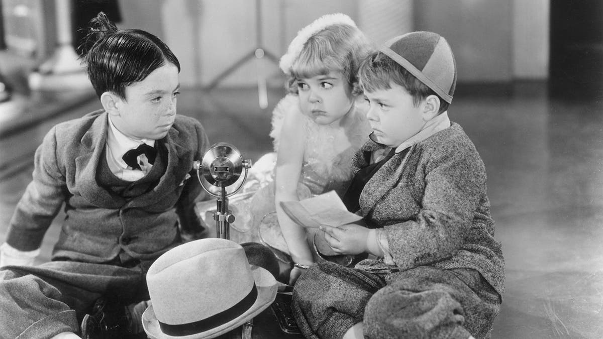 Three child cast members of "Our Gang sitting in a circle and looking at each other.