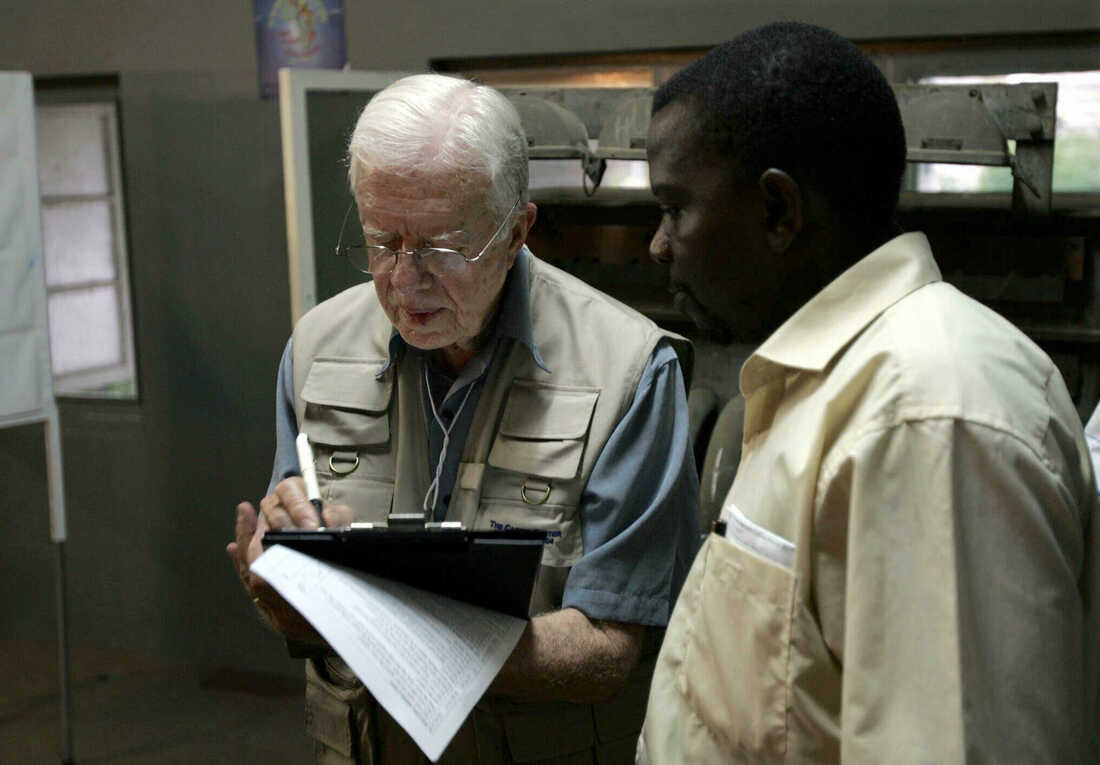December 2, 2004: Former U.S. President Jimmy Carter (L) takes notes while listening to a translater during his polling station observation visit in Maputo, Mozambique. Mozambique's long-time President Joaquim Chissano expressed surprise at the abysmal turn-out in elections to choose his successor, and blamed the poor showing on widespread illiteracy and ignorance of political systems.