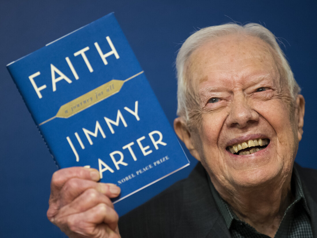 Former U.S. President Jimmy Carter holds up a copy of his book Faith: A Journey For All at a book signing event at Barnes & Noble bookstore on March 26, 2018.