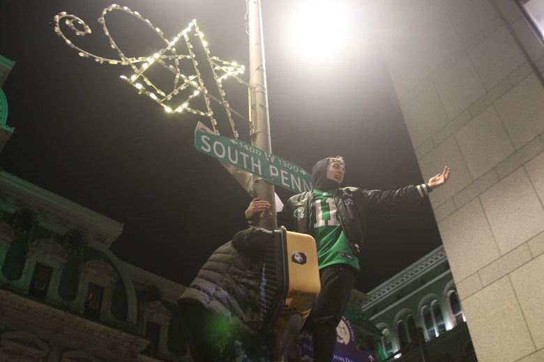 An Eagles fan standing on top of a pole