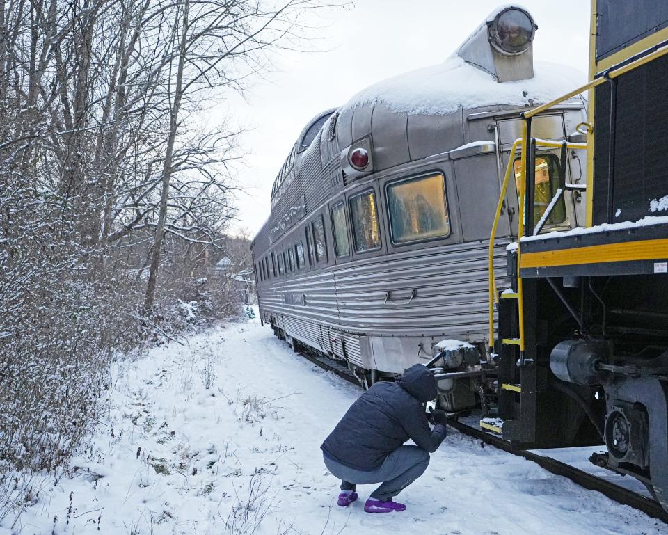 Toni Stutler of Akron takes a picture of the derailed California Zephyr Silver Solarium car in Peninsula on Dec. 22. Four cars from the Cuyahoga Valley Scenic Railroad derailed the previous night on the last run of the North Pole Adventure.