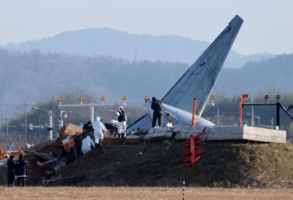 Officials take part in an investigation at the site where a Jeju Air Boeing 737-800 aircraft crashed and burst into flames at Muan International Airport. YONHAP/AFP via Getty Images