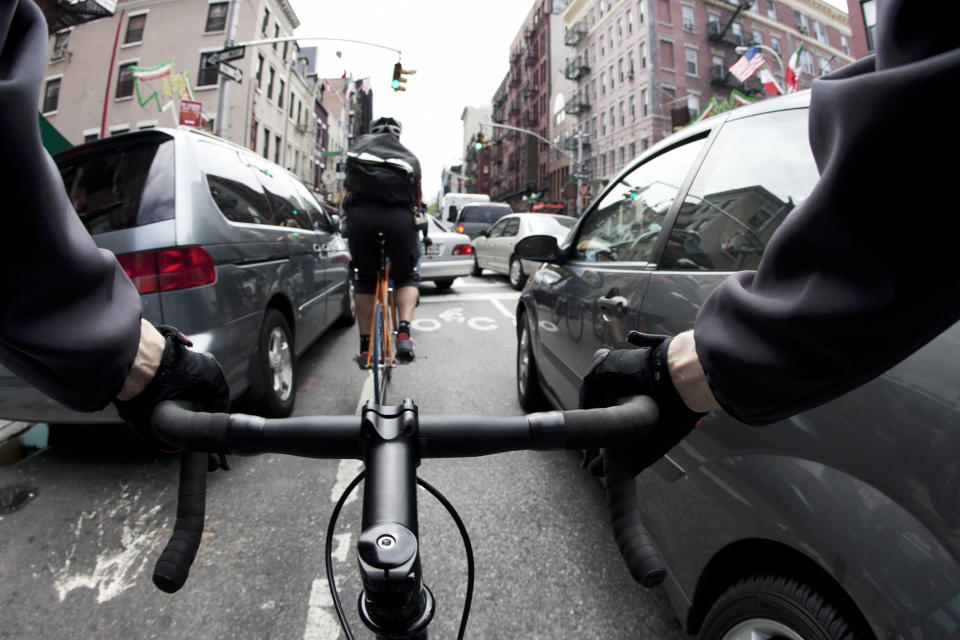 Cyclist&#39;s view of riding a bike through a busy urban street, navigating between vehicles and traffic