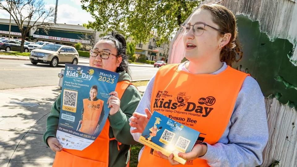 Fresno State pre-dental students Haylee McFall, right, and Rose Xiong pass out Kids Day postcards with QR codes to passing motorists to donate to the annual Kids Day benefit for Valley Children&#x002019;s Hospital, near Fresno State on Tuesday, March 7, 2023.