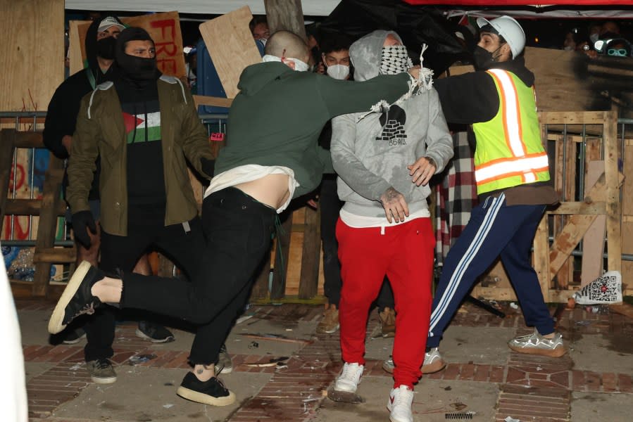 Los Angeles, CA – April 30: Barricades surround the encampment for the Pro-Palestine group as a member, right, is punched by a pro-Israel group member, left, at UCLA on Tuesday, April 30, 2024 in Los Angeles, CA. (Michael Blackshire / Los Angeles Times via Getty Images)