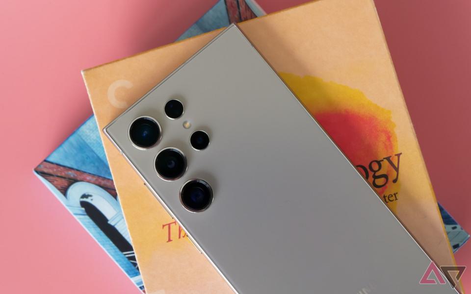 The Galaxy S24 Ultra sitting on two Blu-rays and a pink backdrop.