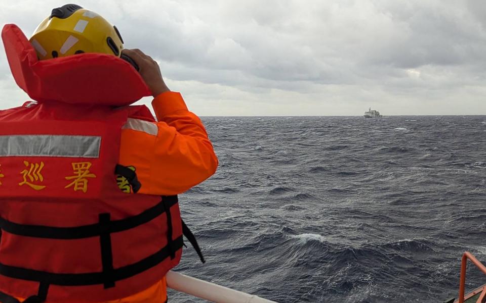 A Taiwan coast guard member watches a Chinese vessel during the incident in early December