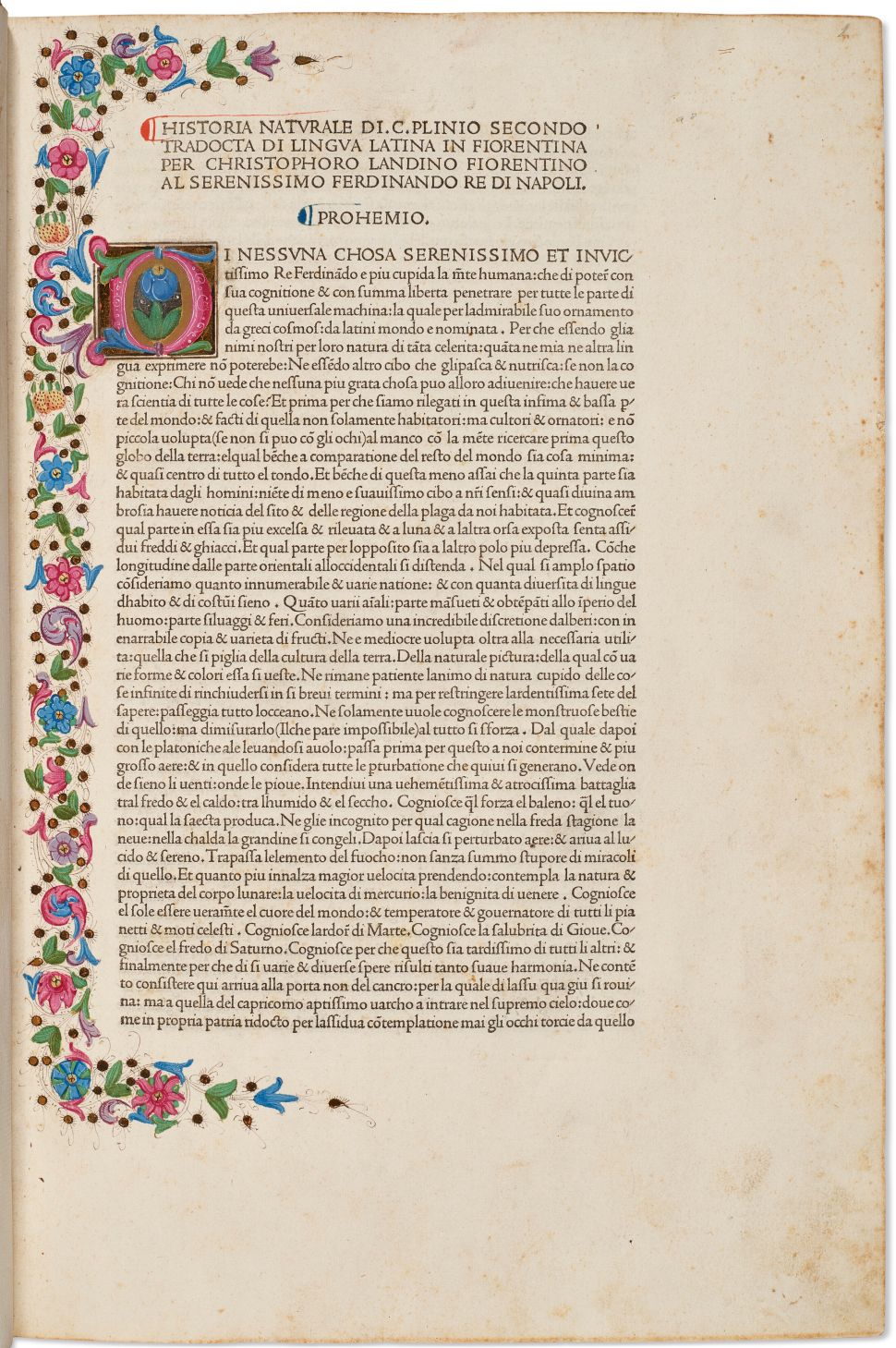 A page from an illuminated manuscript, bordered with colorful floral designs and featuring a decorative initial letter "D" alongside Italian text introducing Pliny the Elder’s Historia Naturalis.