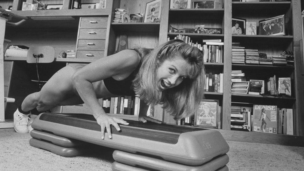 Denise Austin doing a push-up in workout gear from her home