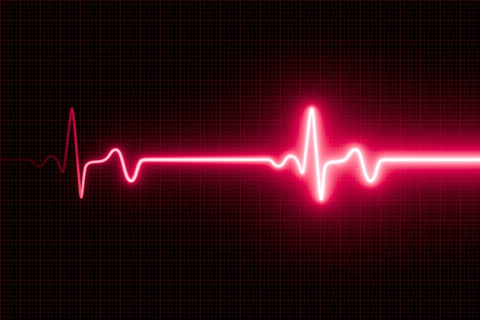 A digital heart rate monitor display shows a pink heartbeat line on a black grid background, indicating a steady pulse