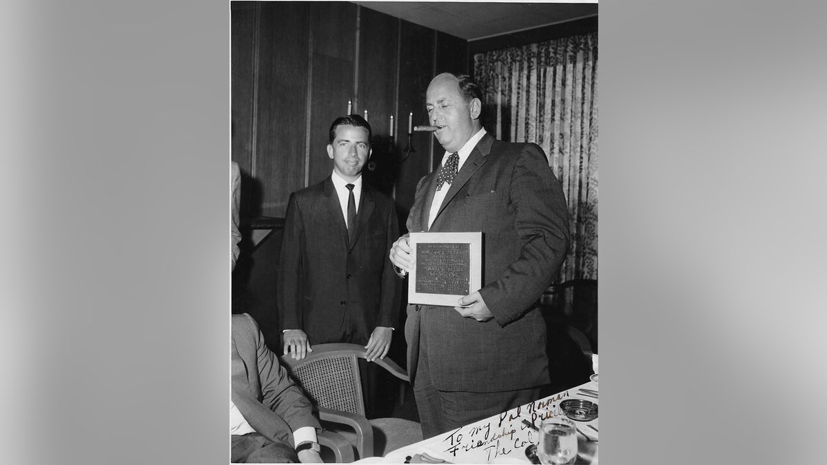 Norman Brokaw posing next to Colonel Tom Parker smoking a cigar