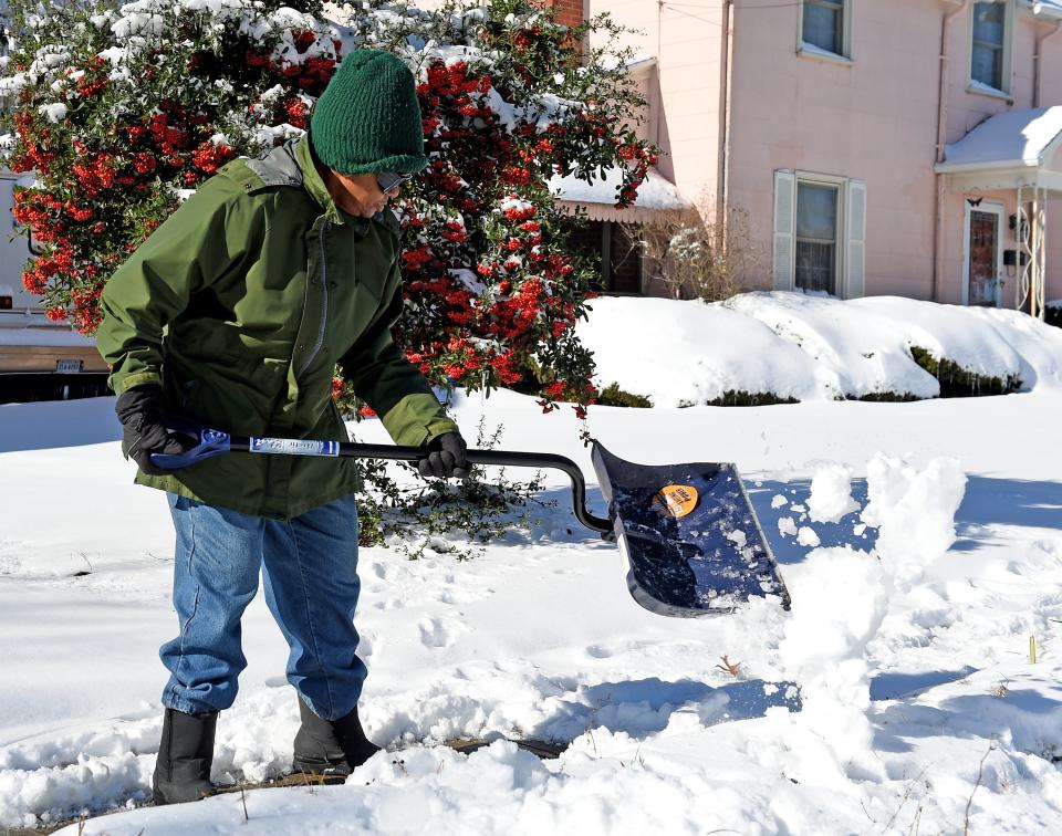 After the snowfall a woman works to clear the snow from the sidewalk in front of her home Tuesday, Jan. 4, 2022, in Salisbury, Maryland.