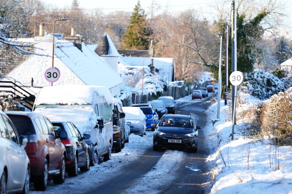 A car drives through snow in Balerno, Edinburgh, on Friday (Andrew Milligan/PA Wire)