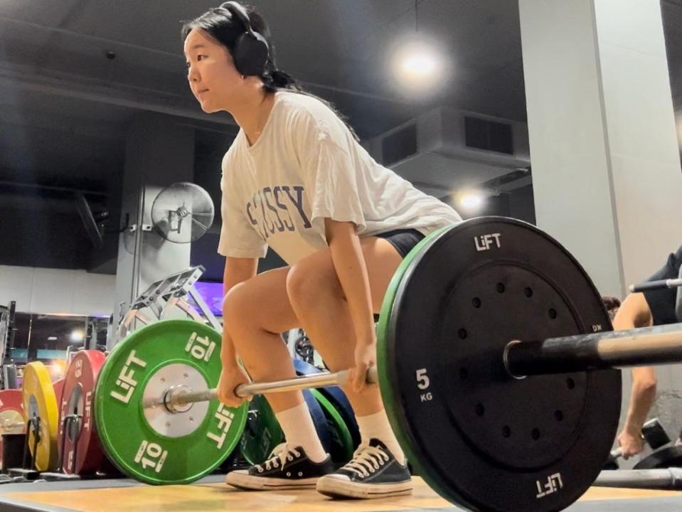 Hanna Kim lifting a heavy barbell in the gym.