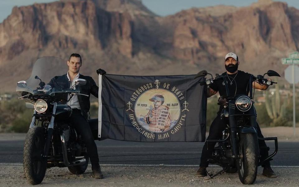 Emmanuel Castillo and an unidentified man on motorbikes holding a banner reading &#39;Orthodoxy or death&#39;