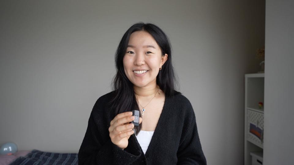 Hannah Kim holds a small microphone and smiles at the camera.