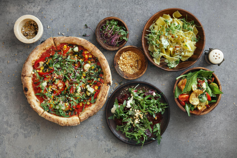 Vegetarian Pappardelle with zucchini and eggplant. Fresh vegetable salad with sun dried tomato, spinach and potato chips. Vegan roasted beetroot salad with arugula, tofu and nuts. Vegetarian pizza with tomato sauce, cauliflower, corn, arugula, nuts and microgreen. Flat lay top-down composition on concrete background.