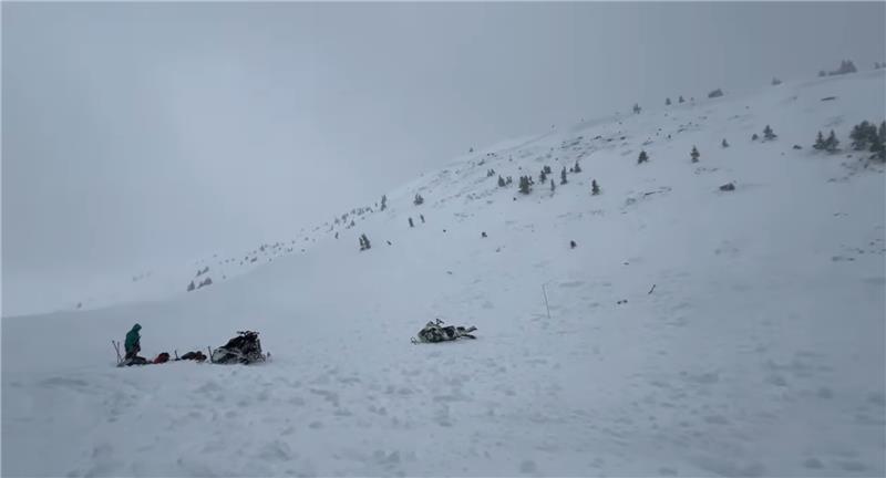 Rescue workers stand on the debris field of an avalanche that buried one person.