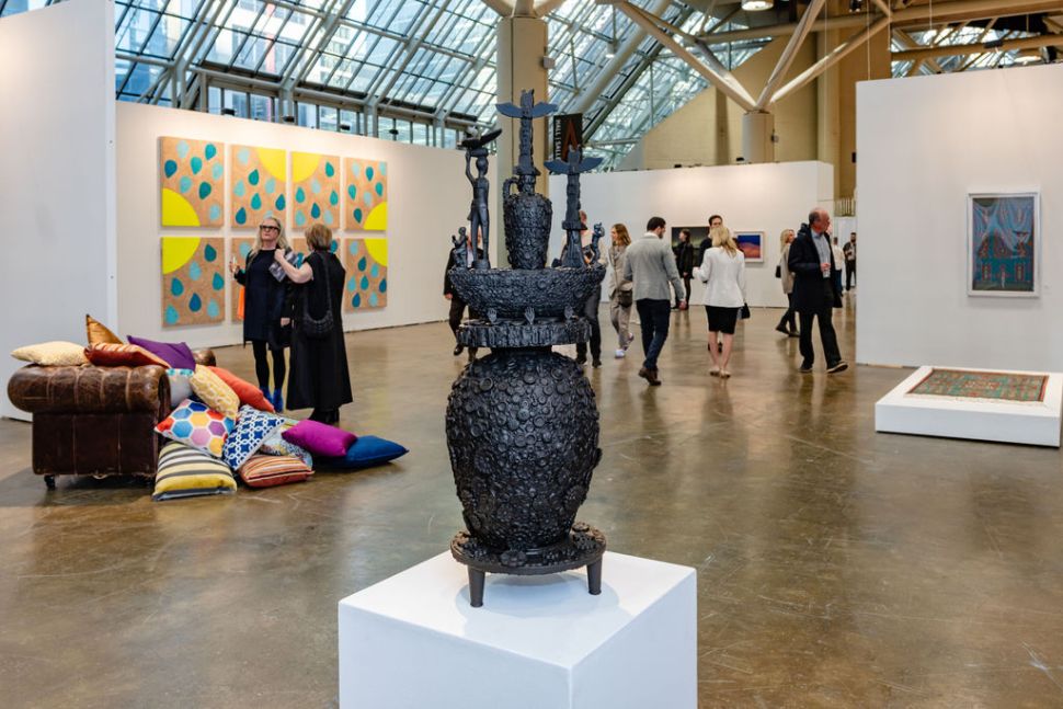 A black sculpture of a vassel in a art fair with people. 