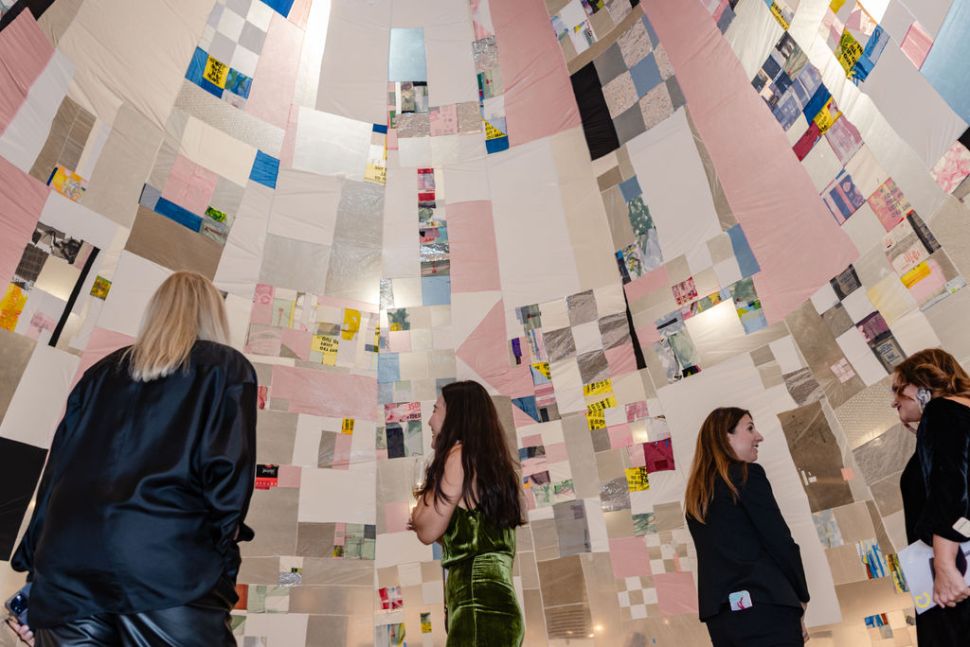 Three women under an installation made of hanging fabrics