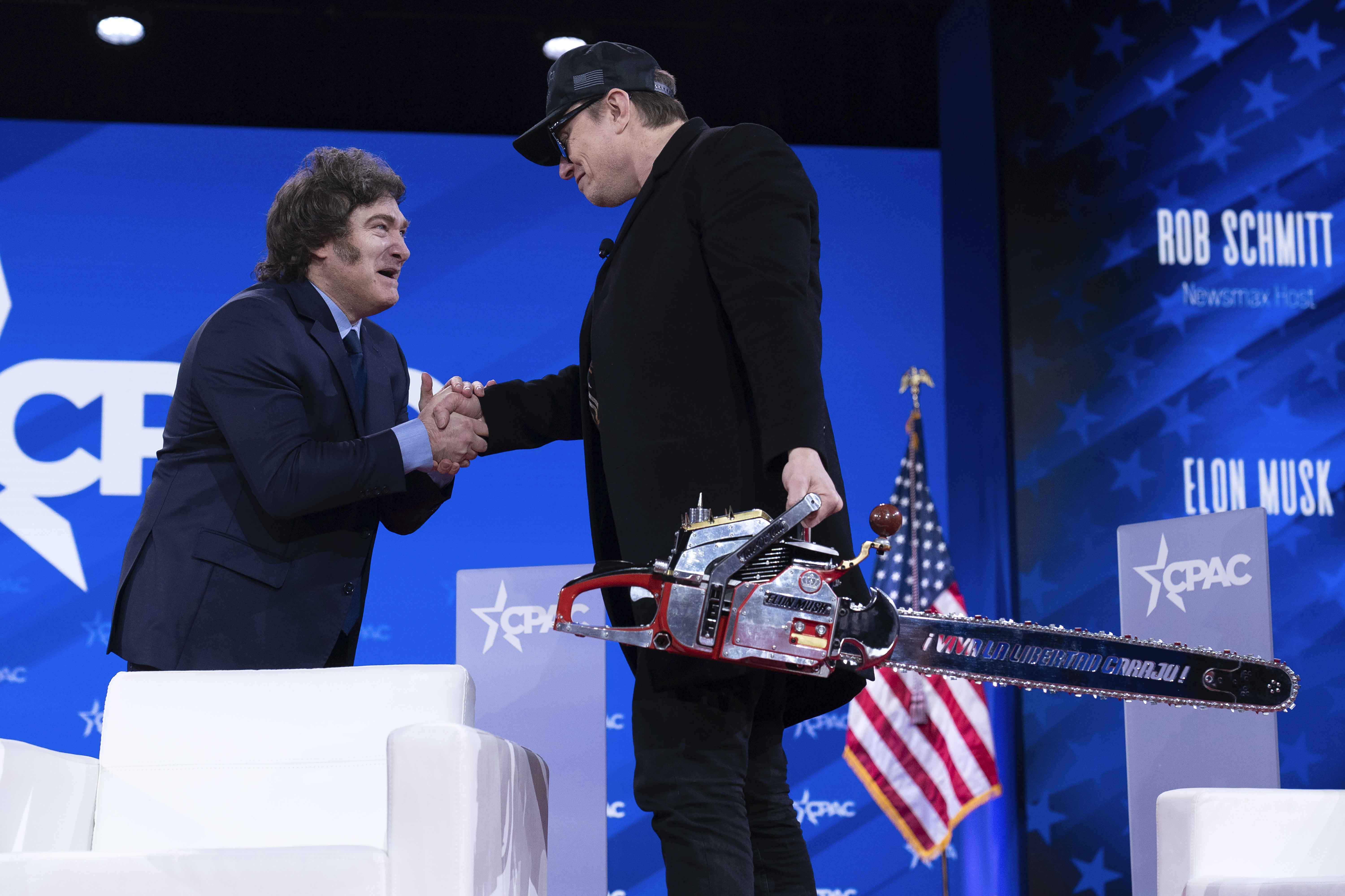 Elon Musk, right, shake hand with Argentina's President Javier Milei after getting a chainsaw from him as they arrive at the Conservative Political Action Conference, CPAC, at the Gaylord National Resort & Convention Center, Thursday, Feb. 20, 2025, in Oxon Hill, Md. (AP Photo/Jose Luis Magana)