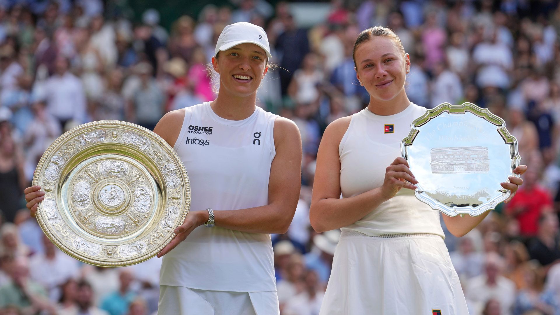 Poland's Iga Swiatek, left, celebrates with trophy after beating Amanda Anisimova of the U.S., right, to win the Wimbledon women's singles final in London, Saturday, July 12, 2025.